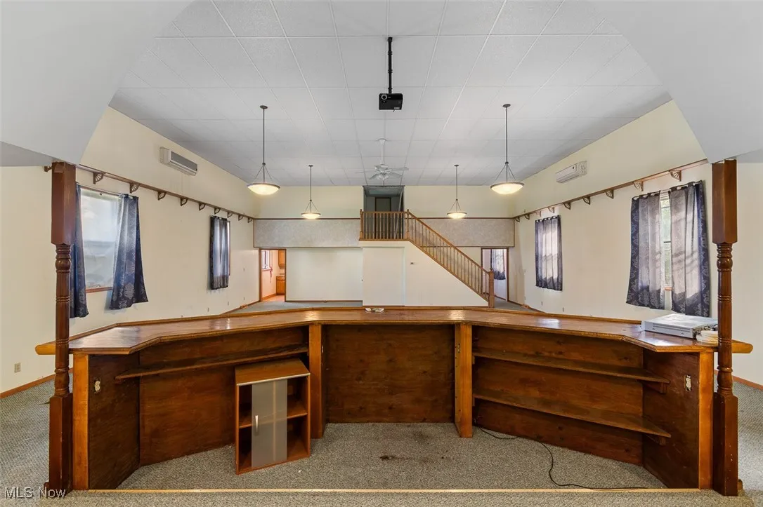 Kitchen with carpet, hanging light fixtures, and a wall mounted air conditioner