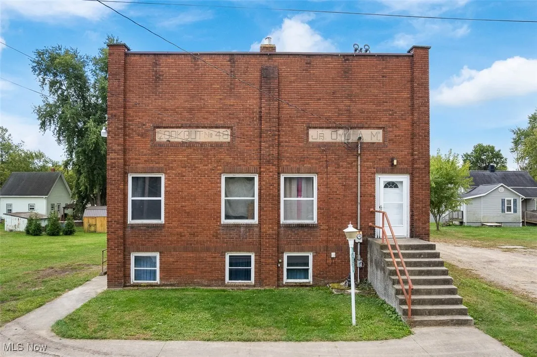 View of front of property with brick siding, a front yard, and a chimney