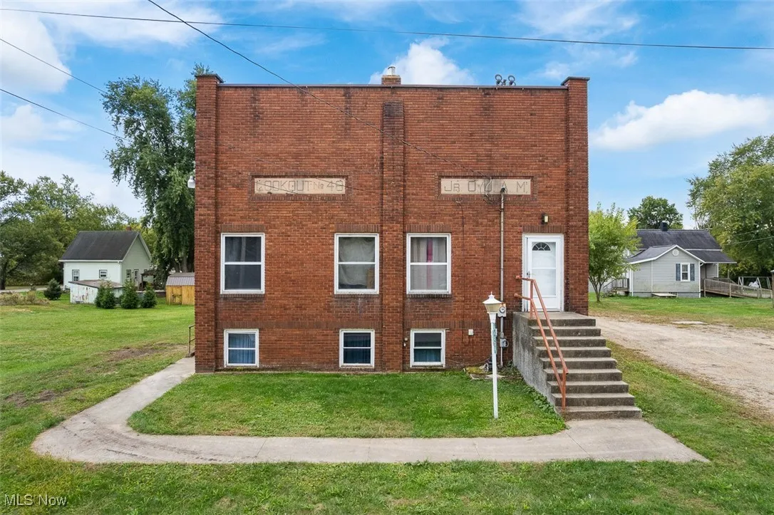 View of front of property featuring brick siding, a front lawn, and a chimney