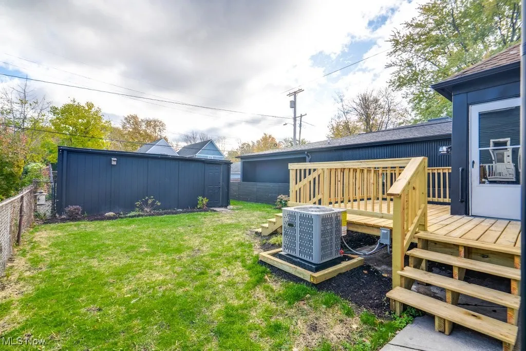 Fenced backyard with a wooden deck, stairs, and an outbuilding