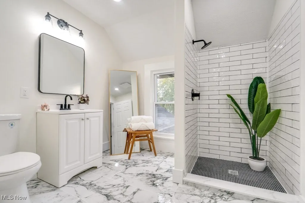 Full bathroom featuring a stall shower, lofted ceiling, vanity, light marble finish floors, and recessed lighting