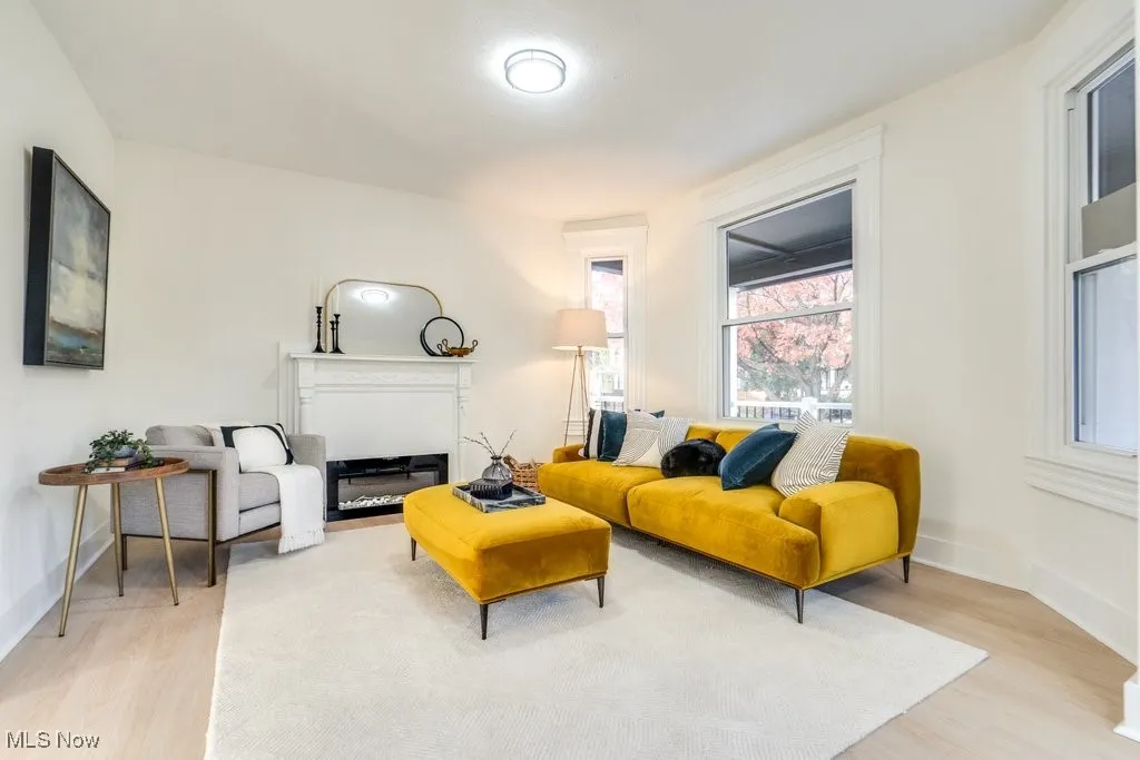 Living area with light wood-type flooring and a glass covered fireplace