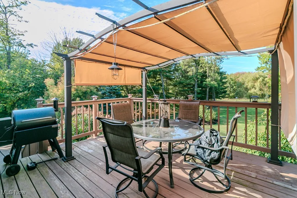 Wooden terrace featuring outdoor dining space and a grill