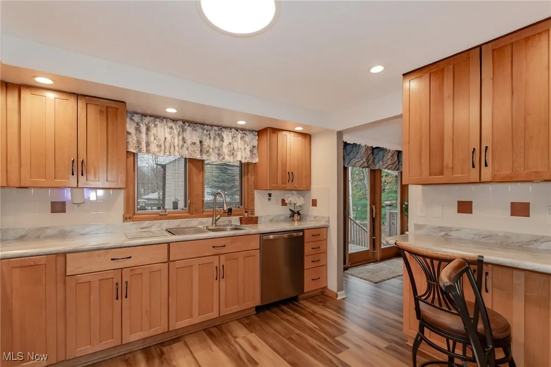 Kitchen featuring decorative backsplash, dishwasher, light wood-style flooring, and recessed lighting