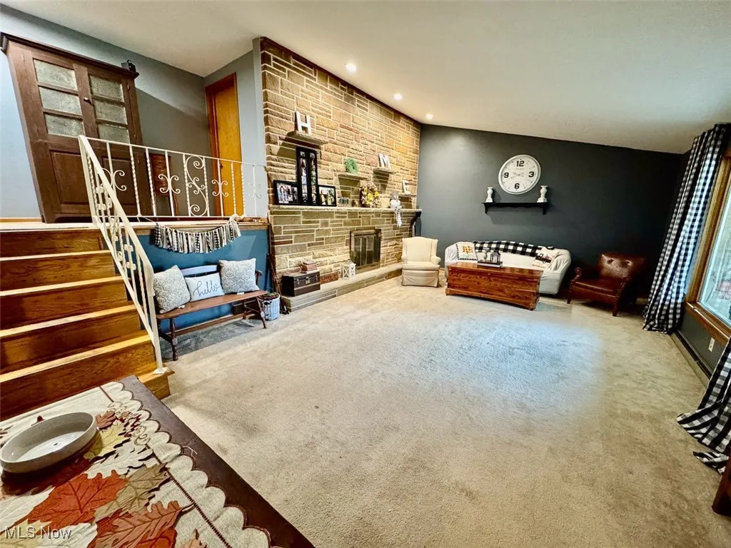 Carpeted living area with stairs, recessed lighting, and a fireplace