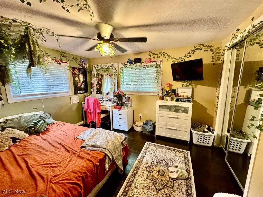Bedroom featuring a textured ceiling, dark wood-style flooring, a ceiling fan, and a closet