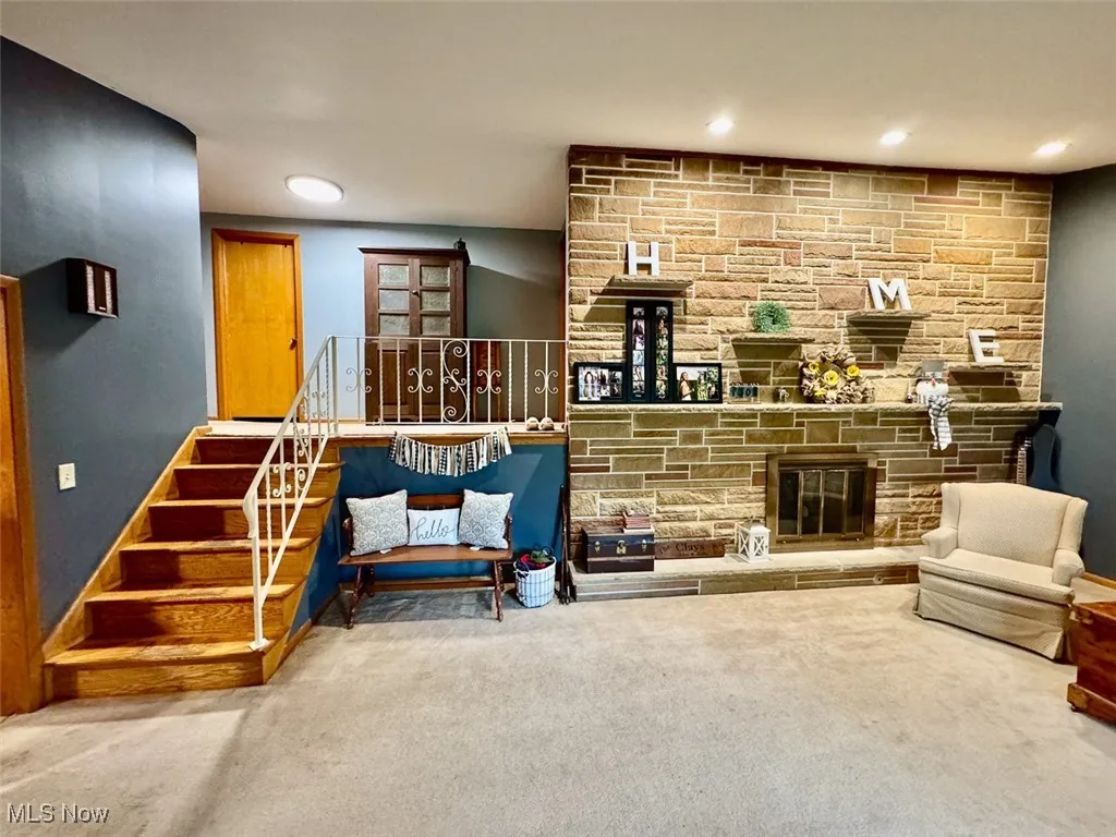 Living area with carpet flooring, recessed lighting, and a stone fireplace