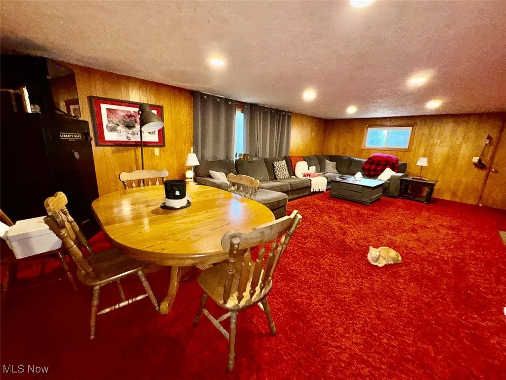 Carpeted family room with wooden walls and a textured ceiling