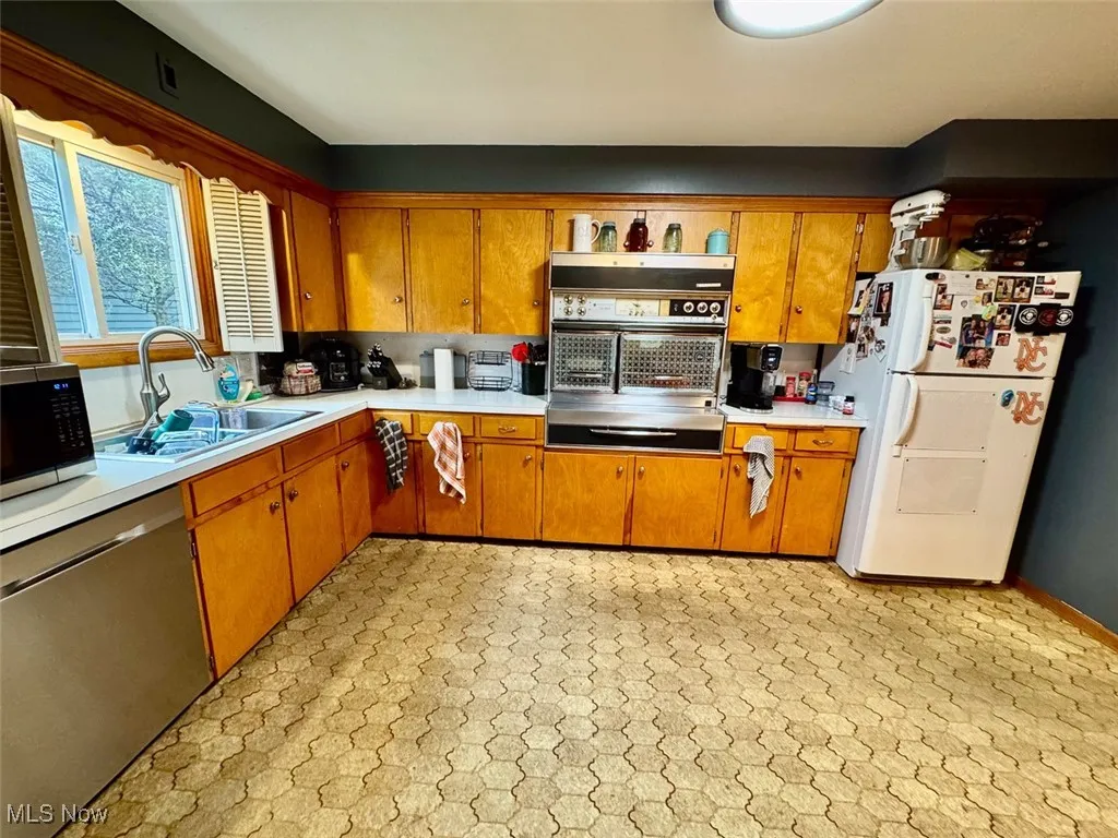 Kitchen featuring light countertops, stainless steel appliances, and brown cabinetry