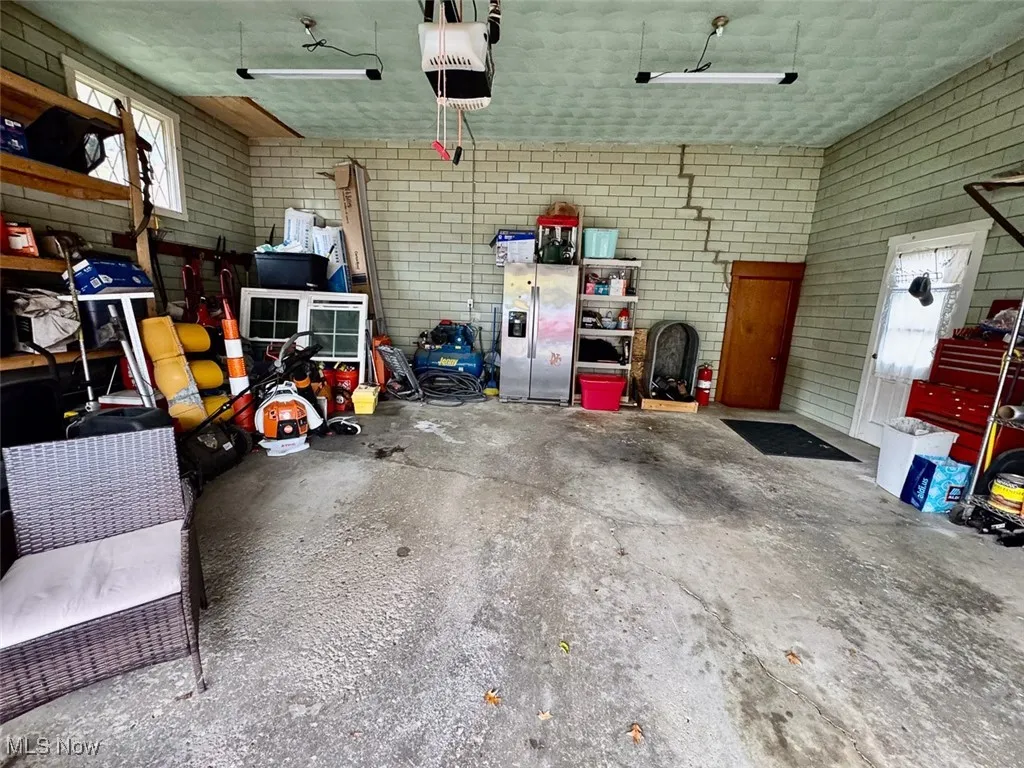 Garage featuring stainless steel fridge and a garage door opener