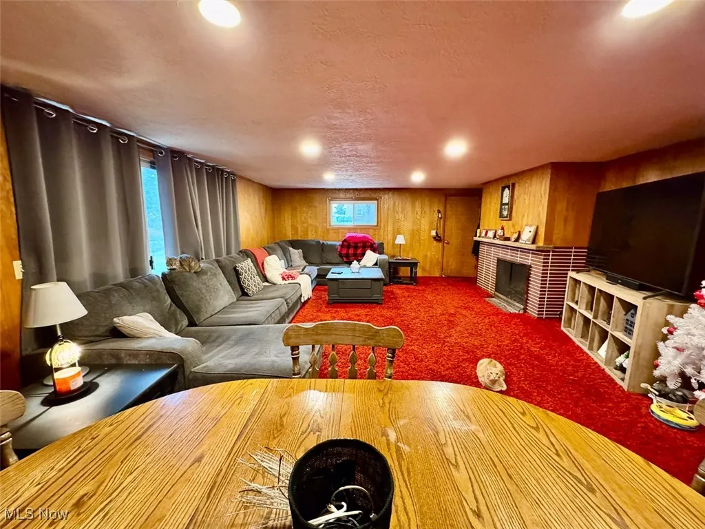 Family room featuring a tiled fireplace, carpet floors, recessed lighting, wood walls, and a textured ceiling