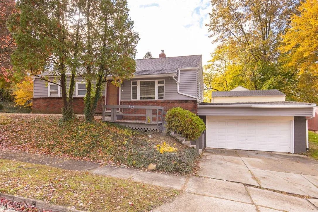 View of front of home with driveway, a chimney, and brick siding