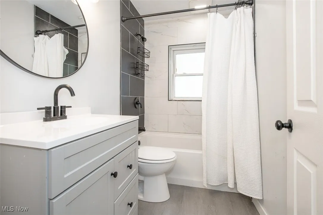 Bathroom featuring vanity, shower / bathtub combination with curtain, and light wood finished floors