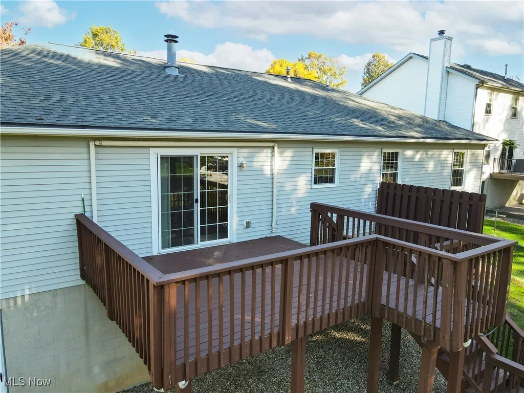 Back of house with a shingled roof, a wooden deck, and a chimney
