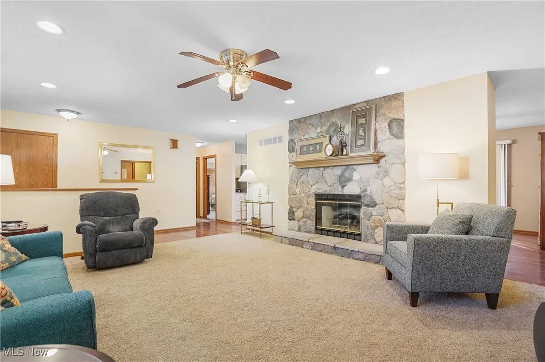 Living room featuring carpet, a ceiling fan, recessed lighting, and a fireplace