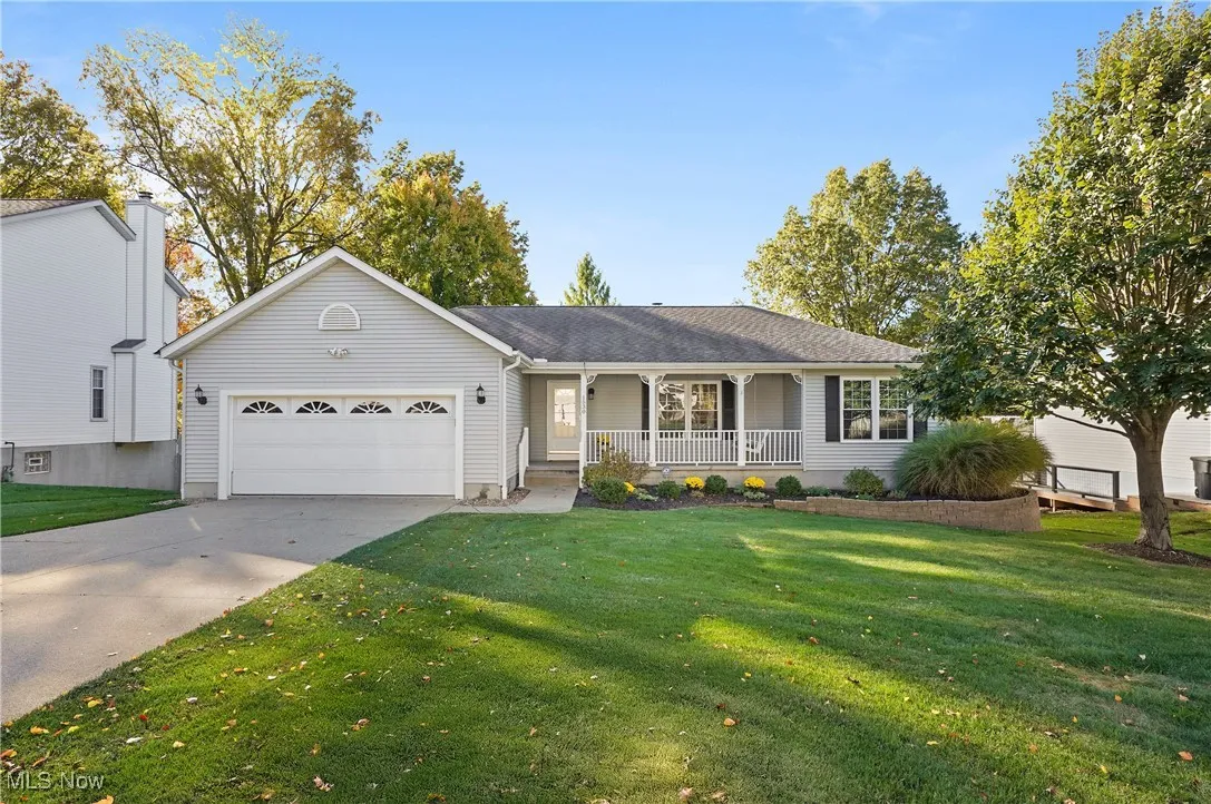 Ranch-style house with covered porch, driveway, a front yard, and a garage
