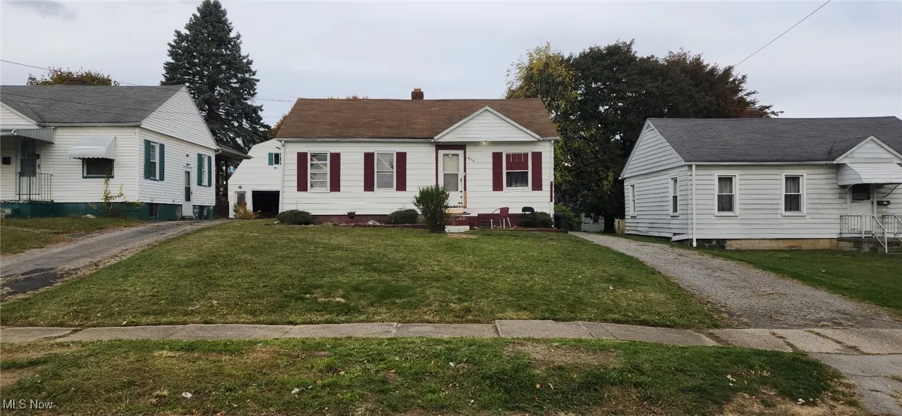 Bungalow-style house featuring driveway, a front yard, and a chimney