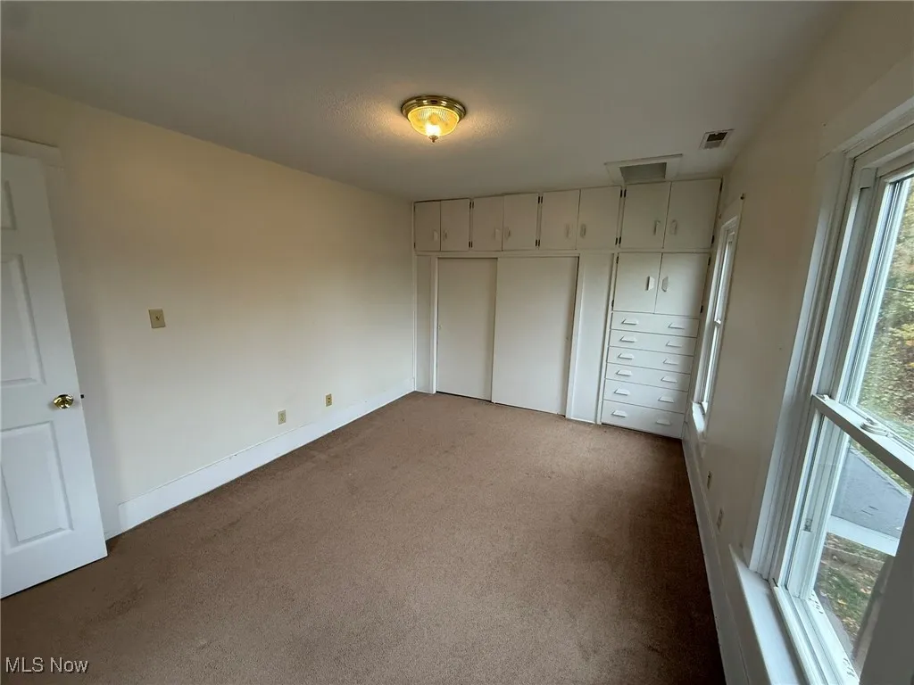 Unfurnished bedroom featuring a closet and dark carpet