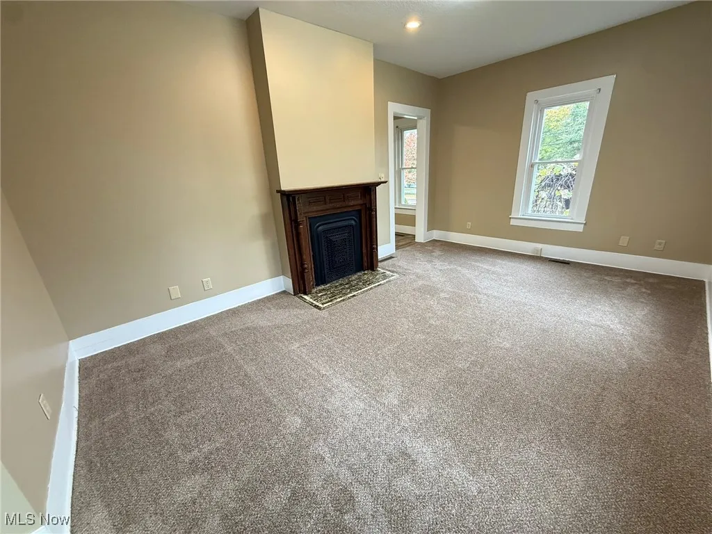 Unfurnished living room featuring carpet and a fireplace with flush​​‌​​​​‌​​‌‌​‌‌​​​‌‌​‌​‌​‌​​​‌​​ hearth