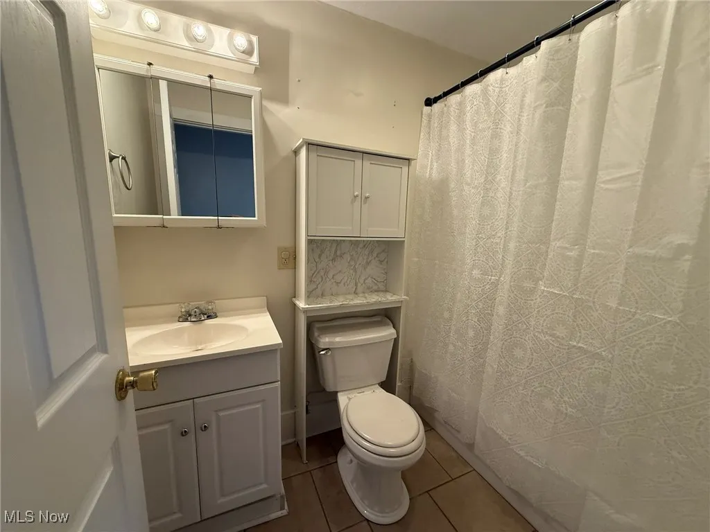 Bathroom featuring vanity, curtained shower, and dark tile patterned floors