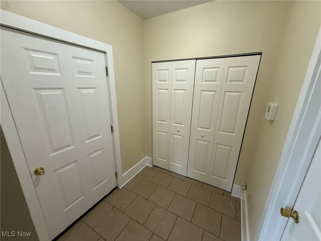 Corridor with dark tile patterned flooring and baseboards