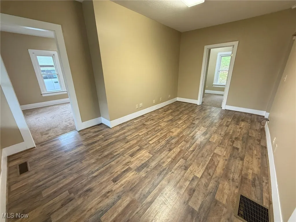Spare room featuring dark wood-style floors and baseboards