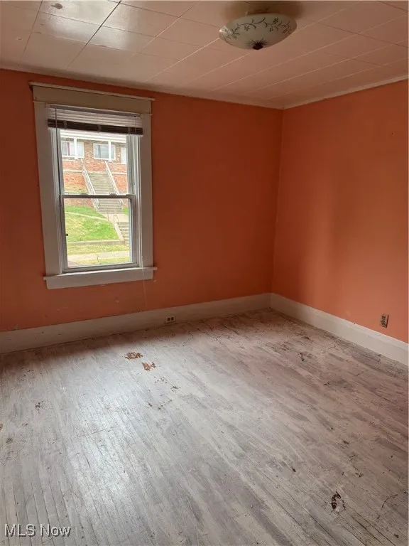Empty room with hardwood / wood-style floors and baseboards