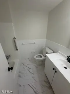 Bathroom featuring vanity, wainscoting, and light marble finish floors