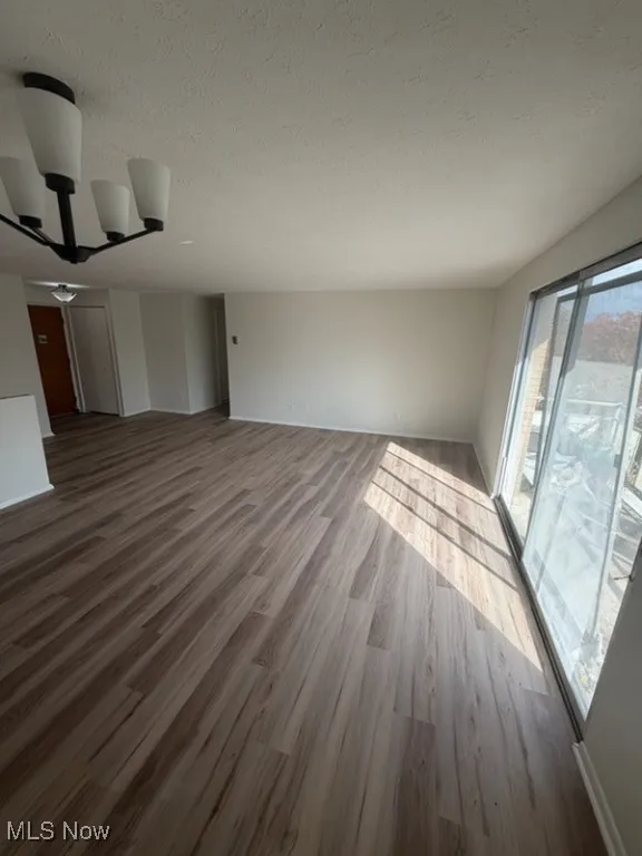 Unfurnished living room featuring wood finished floors and a textured ceiling