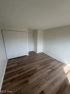 Unfurnished bedroom with dark wood-style flooring and a closet