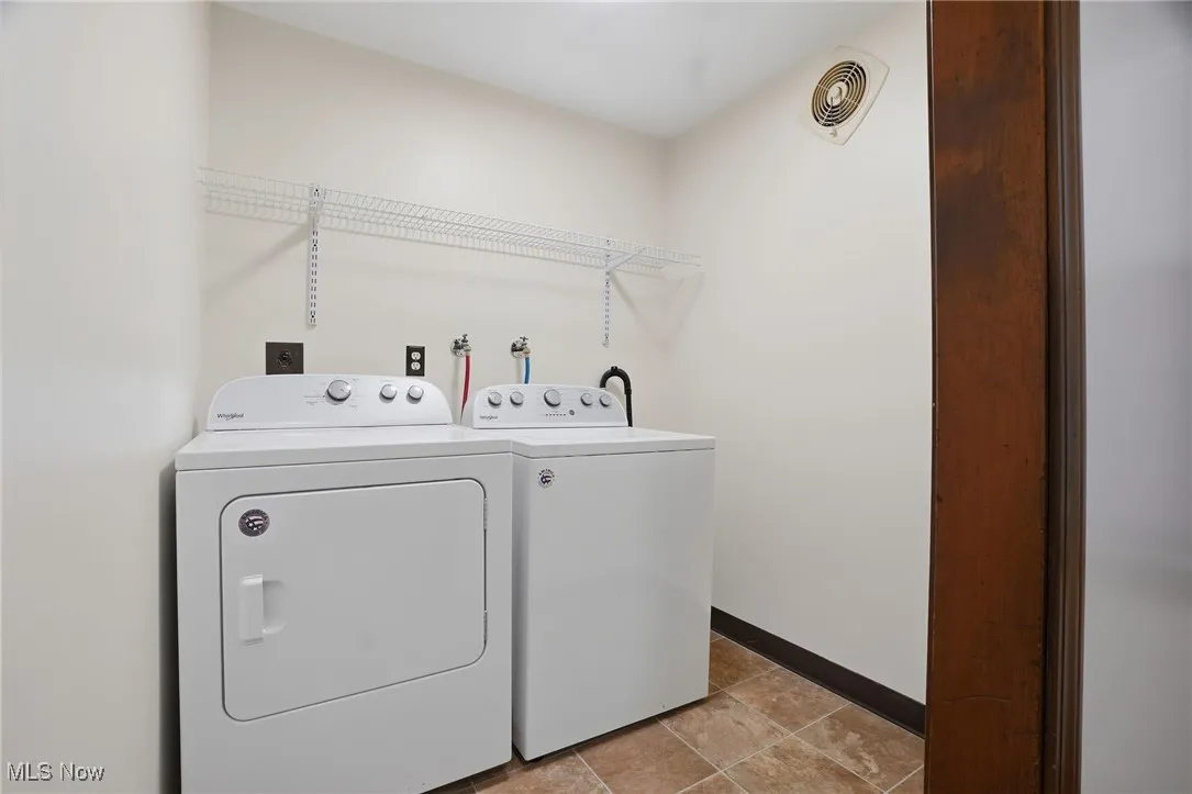 Washroom with washer and dryer and light tile patterned floors
