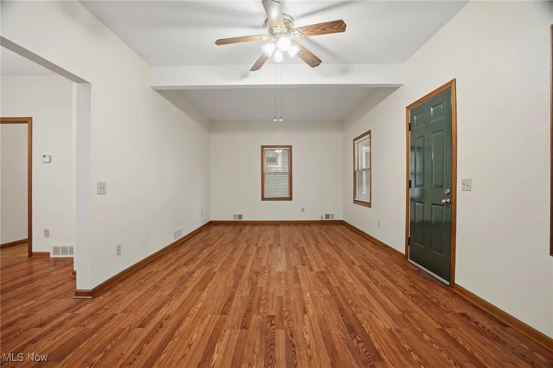 Spare room with wood finished floors, ceiling fan, and beam ceiling
