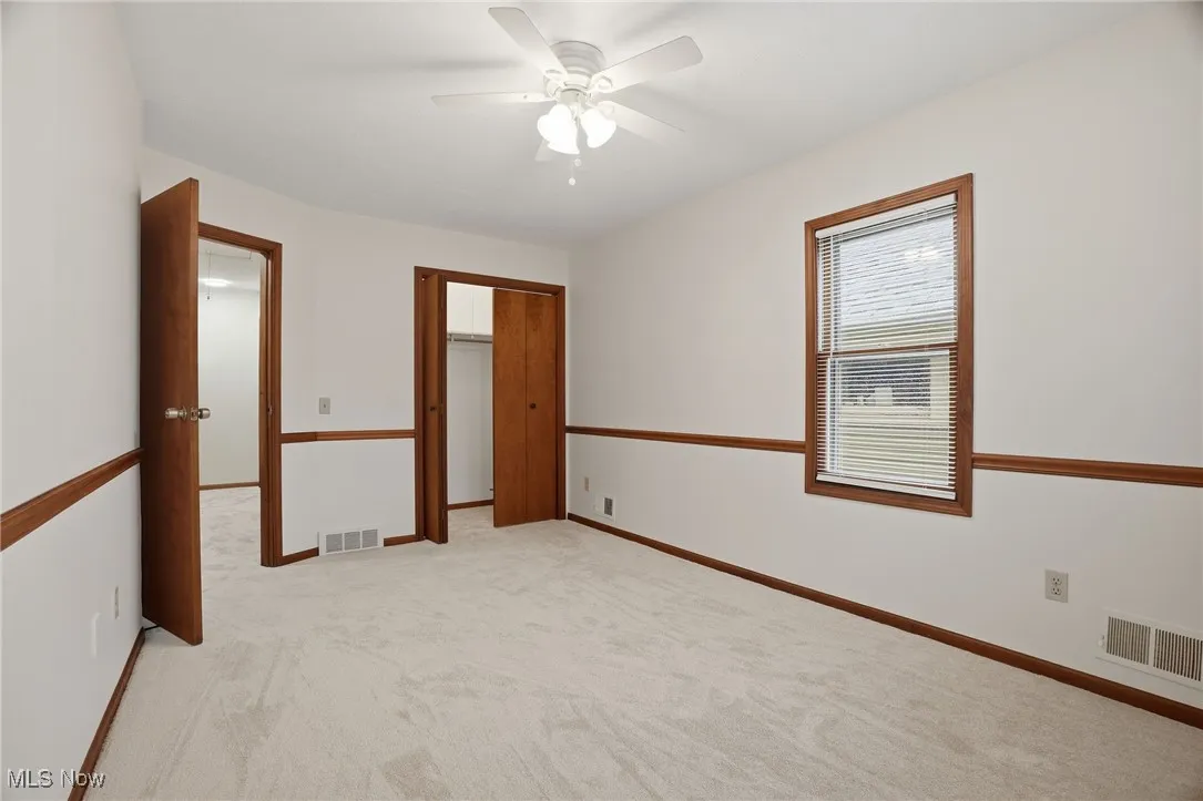 Unfurnished bedroom with light carpet, ceiling fan, and a closet