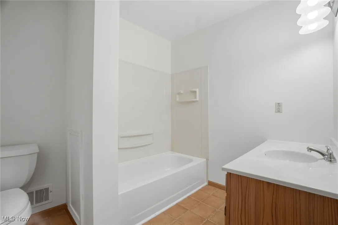 Bathroom featuring vanity, light tile patterned flooring, and washtub / shower combination