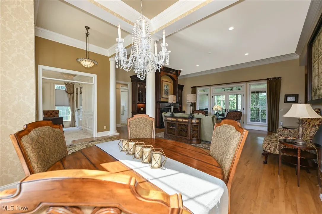 Dining space with healthy amount of natural light, crown molding, decorative columns, recessed lighting, and wood floors.