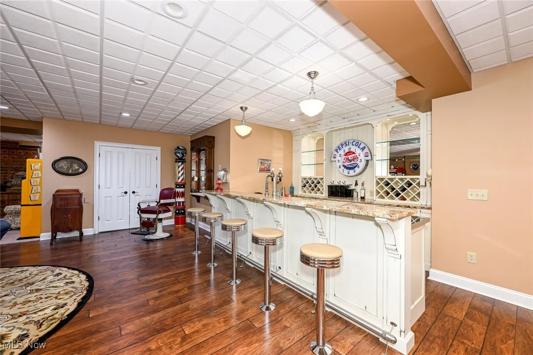 Kitchen featuring pendant lighting, a kitchen bar, light stone countertops, dark wood-type flooring, and recessed lighting