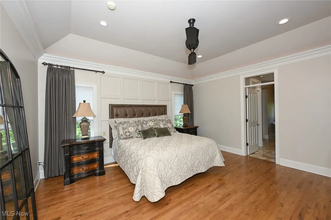 Bedroom featuring hardwood floors, recessed lighting, a raised ceiling, and ornamental molding