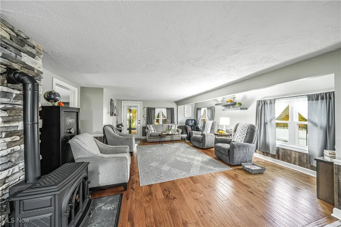 Living room featuring a wood stove, a textured ceiling, hardwood / wood-style flooring, and plenty of natural light