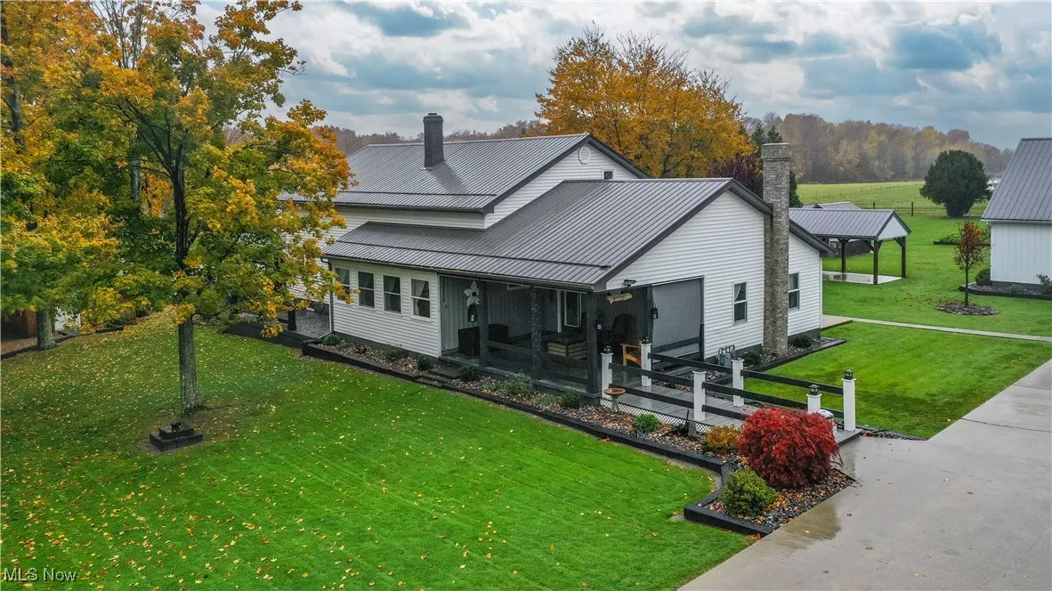 View of front of property featuring a front lawn, a chimney, and a metal roof