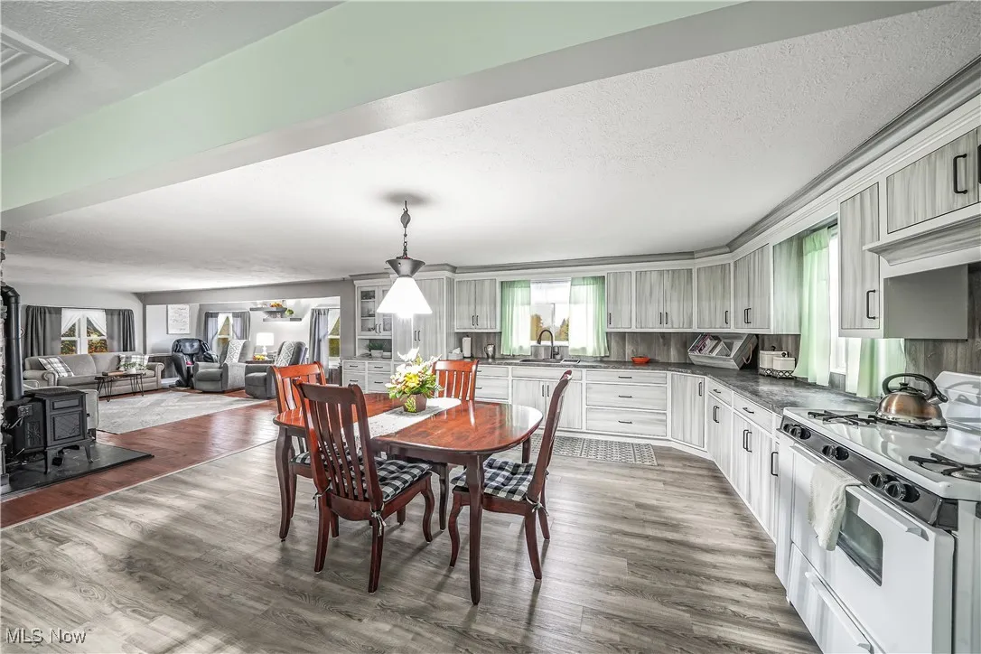 Dining room featuring a wood stove, a textured ceiling, and wood finished floors