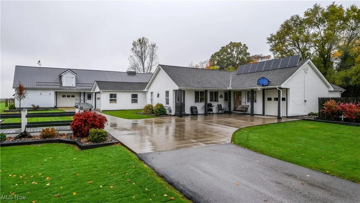 View of front of property with driveway, an attached garage, a porch, and solar panels
