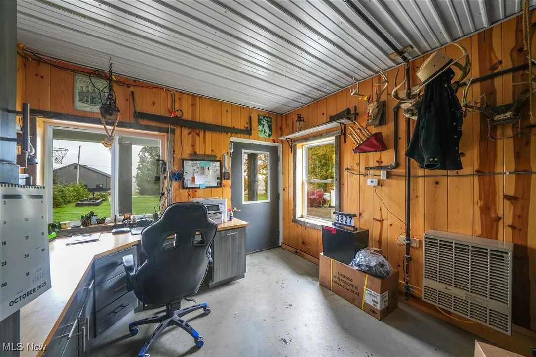 Office featuring concrete floors, wooden walls, and heating unit