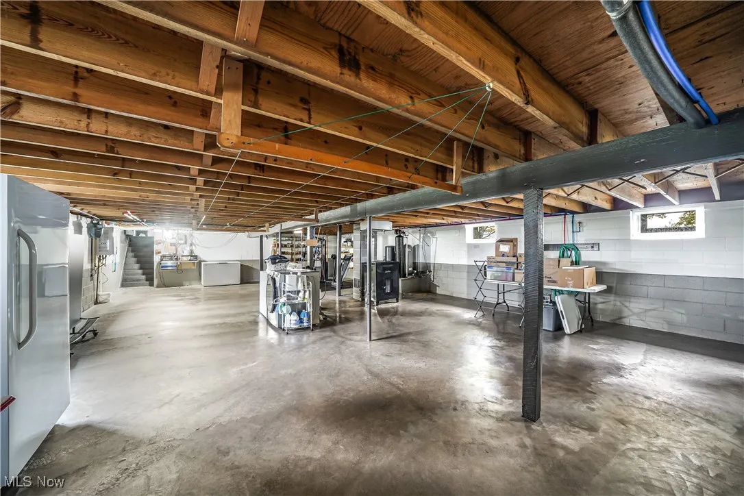 Basement with stairway and stainless steel fridge