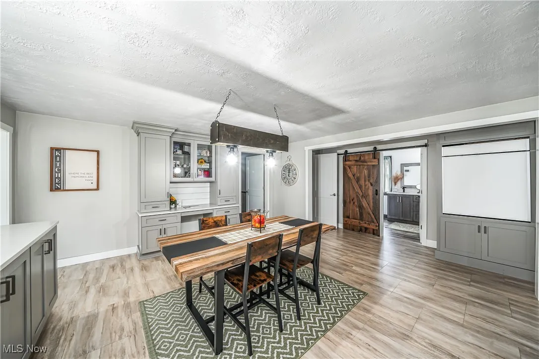 Dining area with a textured ceiling, a barn door, and light wood finished floors