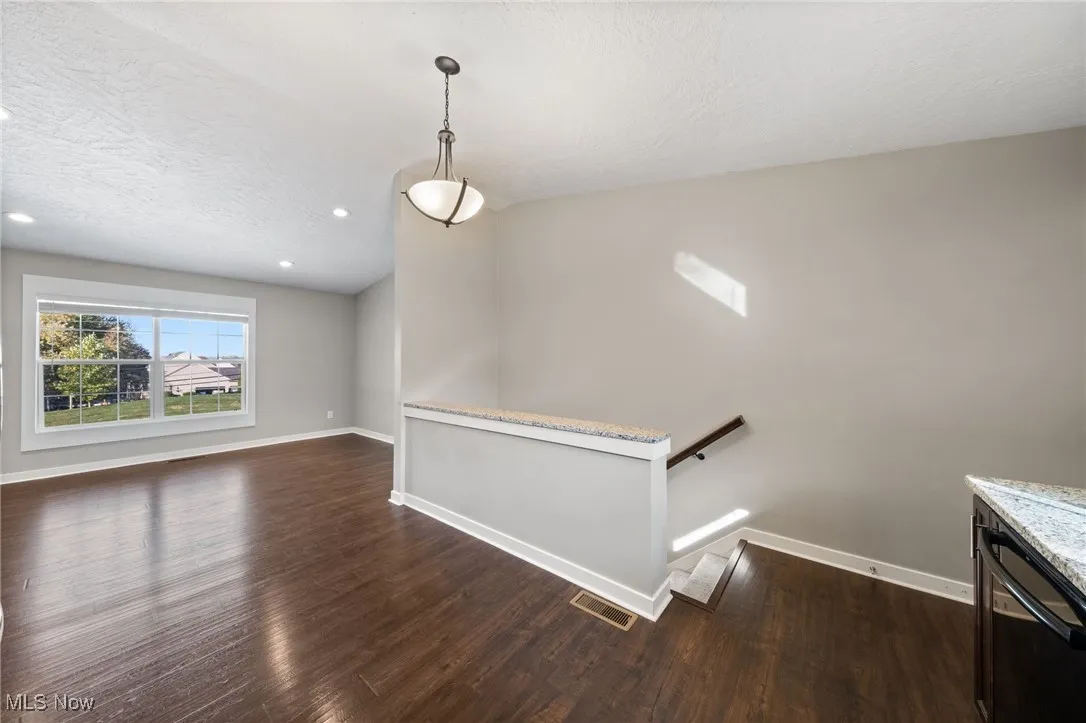 Unfurnished dining area featuring dark wood finished floors, a textured ceiling, and recessed lighting