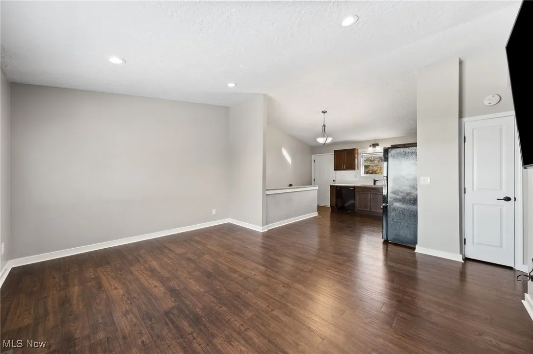Unfurnished living room with dark wood-type flooring, recessed lighting, and a textured ceiling