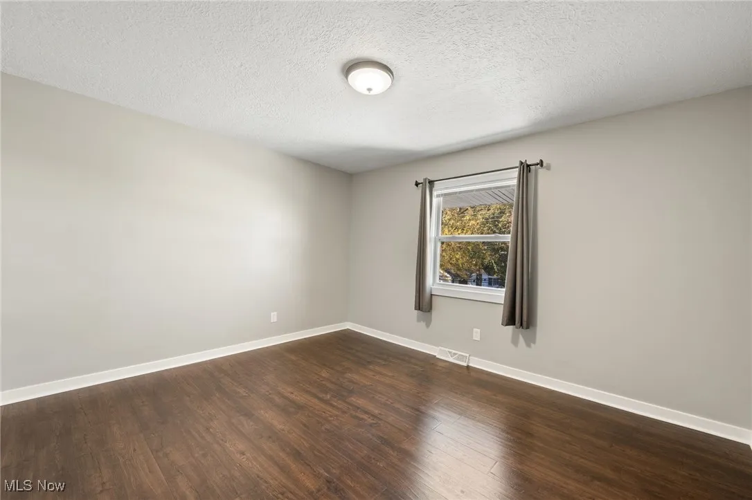 Empty room featuring a textured ceiling and dark wood finished floors