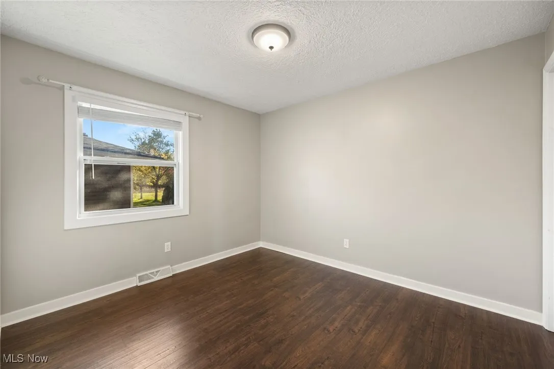 Spare room with a textured ceiling and dark wood finished floors