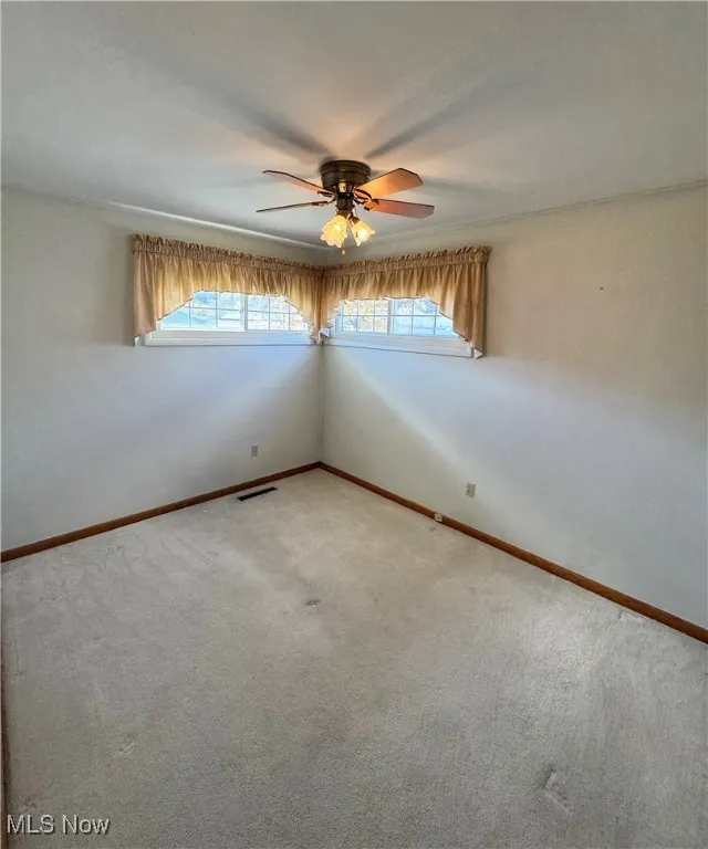 Empty room with a ceiling fan and carpet floors