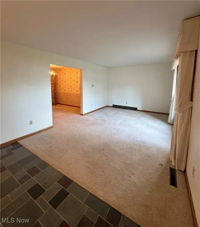 Unfurnished room featuring dark carpet and baseboards
